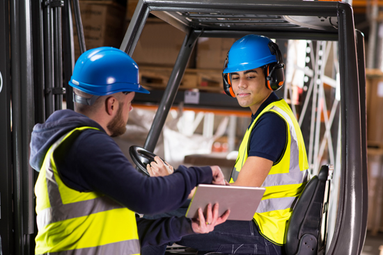 warehouse supervisor chats to young forklift truck driver trainee