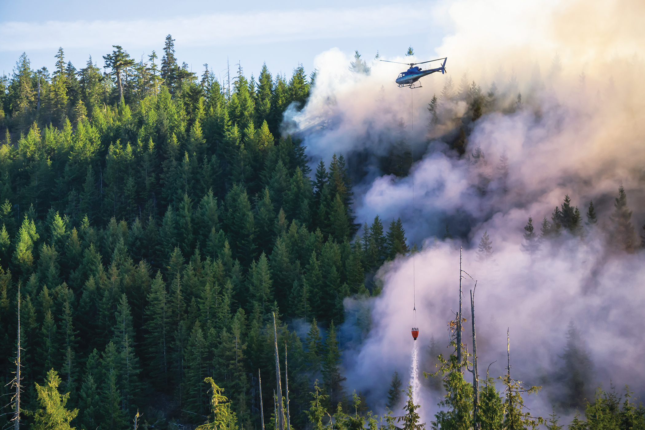 Helicopter fighting BC forest fires during a hot sunny summer da