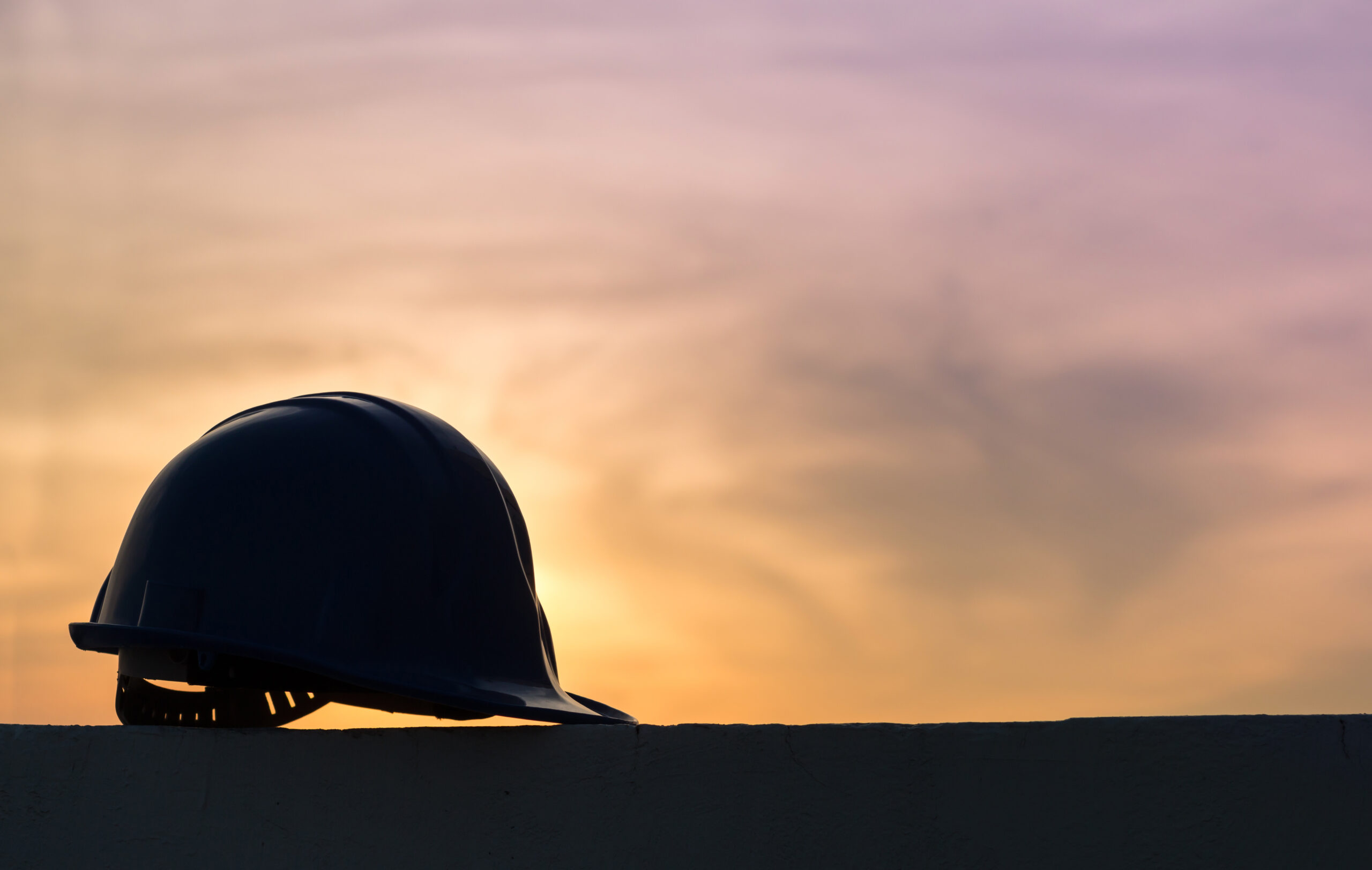 The safety helmet silhouette at construction site with sunset ba